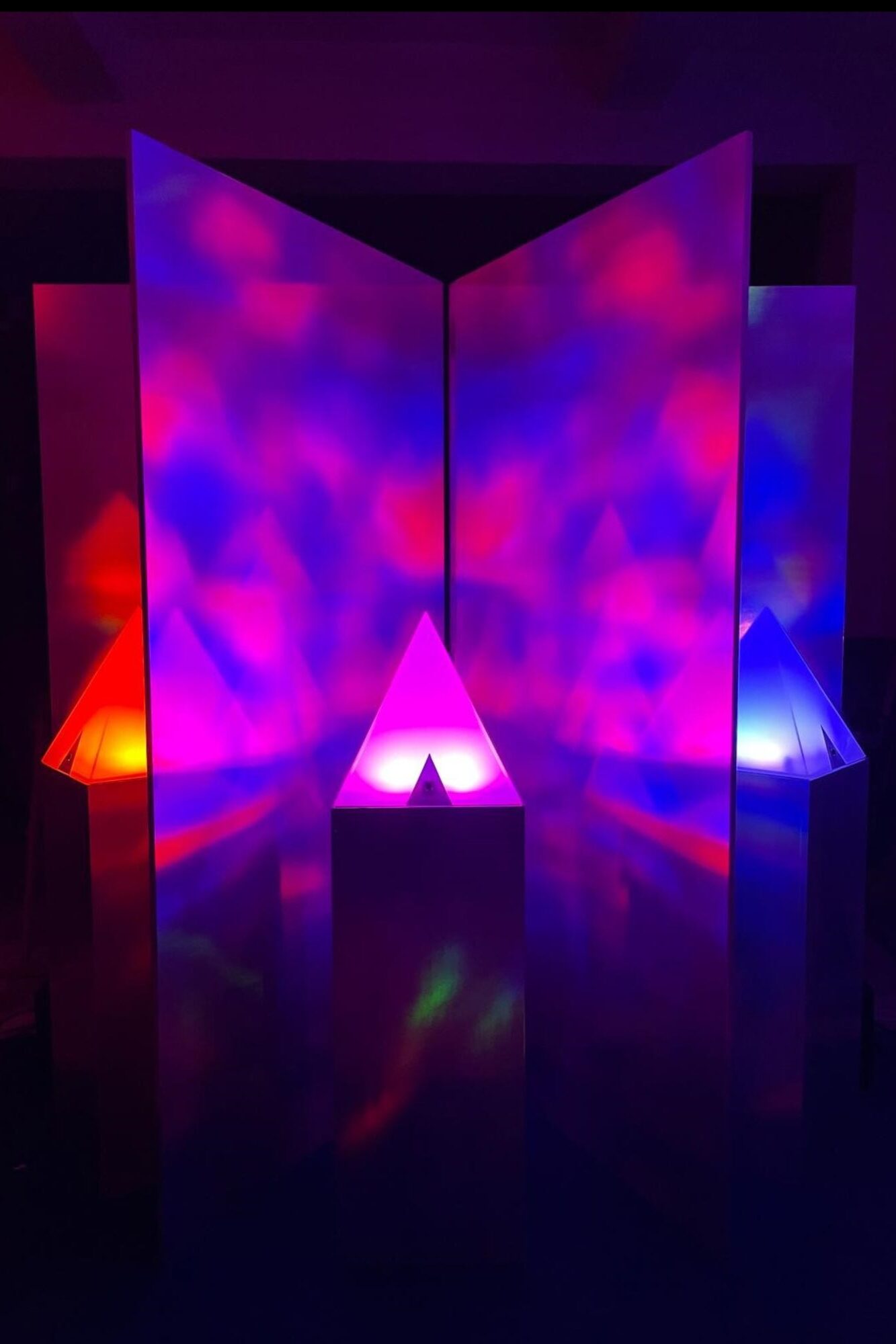Art and Science Exhibition - a glowing, multi-sensory environment where light and sound responded to the presence of people. Prism in different colors project onto walls in 90° arrangements.